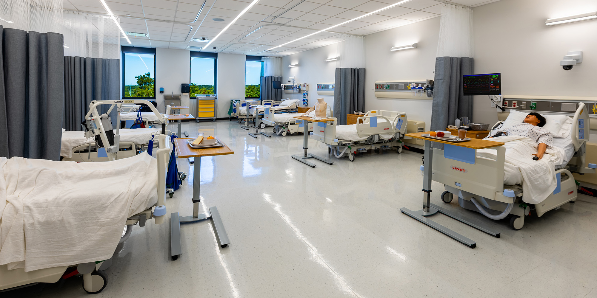 Simulation room designed to replicate a hospital ward with overhead curtains and patient monitoring